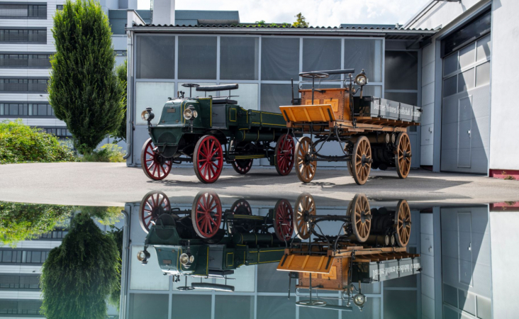 Replika prvního nákladního automobilu z roku 1896 ve společnosti dochovaného vozu z roku 1898 s motorem umístěným v přední časti. 